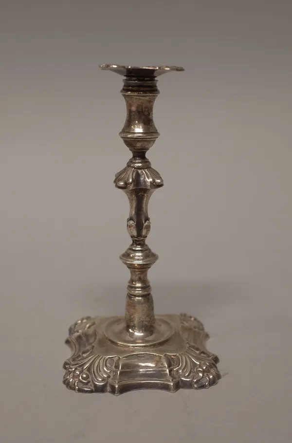 A silver taper stick decorated with a knopped stem raised on a shaped square base with partly fluted corners, London mid 18th century (hallmarks indis