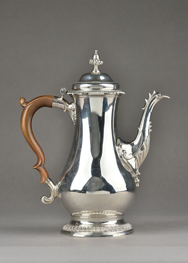 An early George III silver coffee pot, of baluster form, decorated with gadrooned rims, with a fluted acorn shaped finial, fitted with a wooden handle