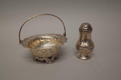 A George III silver basket, of shaped circular form, with embossed and pierced decoration and with a swingover handle, London 1760 and a silver pepper
