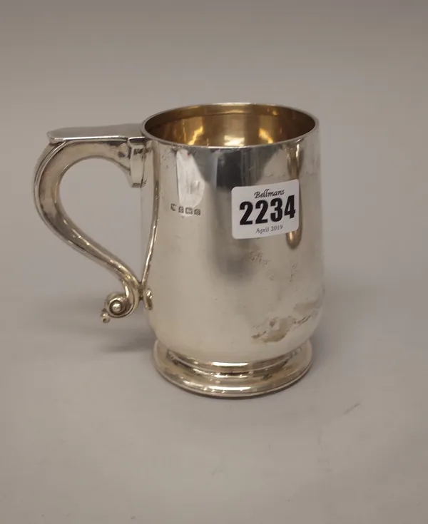 A silver mug with a scrolling handle, raised on a circular foot, the body plain, Birmingham 1927, height 12cm, weight 238 gms.