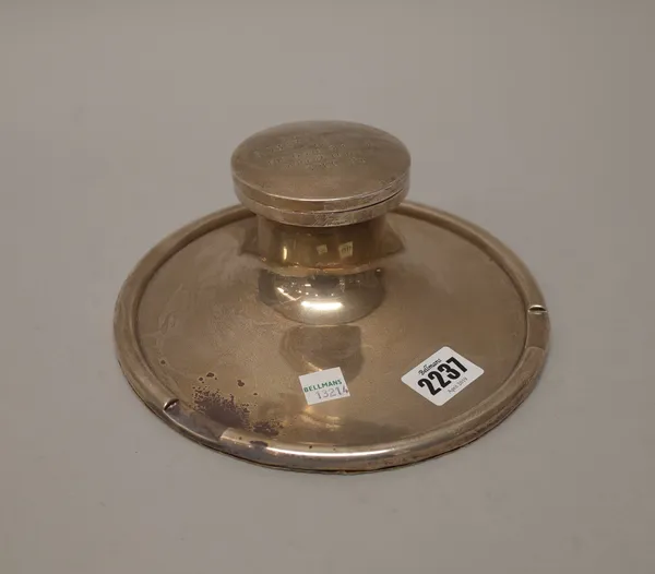 A silver hinge lidded inkstand, of circular form, the front with a pen recess, the cover presentation inscribed, fitted with a glass liner, Birmingham