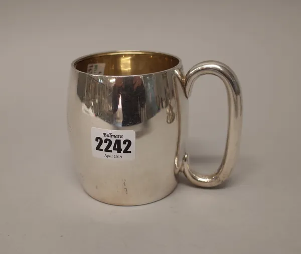 A silver mug of barrel shaped form, with a 'C' shaped handle, the body presentation inscribed, Birmingham 1931, height 9.5cm, weight 250 gms.