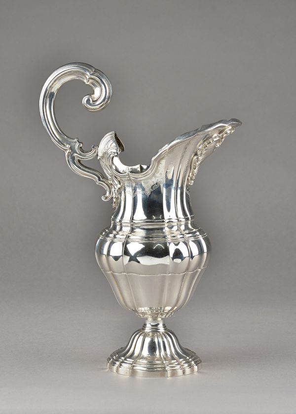 An Italian ewer, the body of panel shaped baluster form, with a bold scrolling handle, cast cartouche to the lip, with engraved borders below a reeded