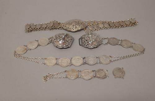 A waist belt spaced with Burmese coins at intervals, the two piece clasp decorated with Burmese deity style figures and an Asian waist belt, the links