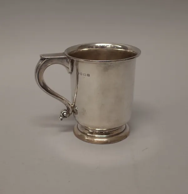 A silver mug with a scrolling handle, raised on a circular foot, the body presentation inscribed, height 11.5cm, Birmingham 1931, weight 303 gms.