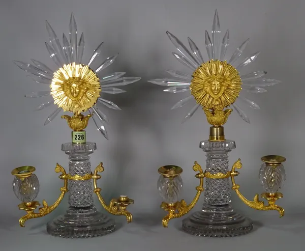 Manner of Versace; a pair of cut glass and gilt metal mounted twin branch candelabra with "Roi Soleil" decorative motif (2).