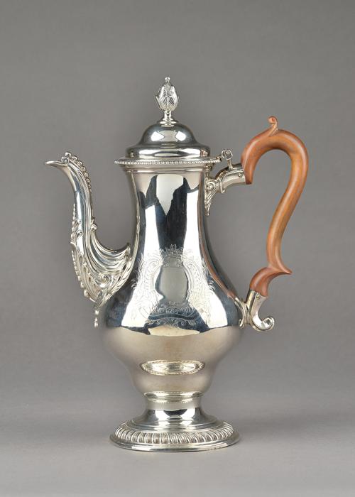 An early George III silver coffee pot, of baluster form, raised on a gadrooned circular foot, the body with a later engraved cartouche,  the hinged li