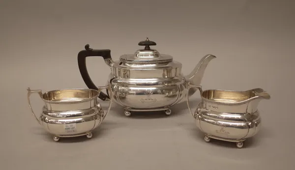 A silver three piece tea set, comprising; a teapot, a twin handled sugar bowl and a milk jug, each piece of shaped oval form, crest and motto engraved