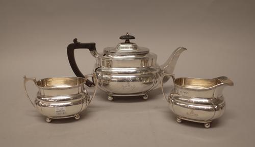 A silver three piece tea set, comprising; a teapot, a twin handled sugar bowl and a milk jug, each piece of shaped oval form, crest and motto engraved