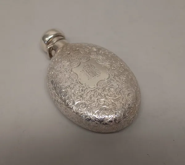 A Victorian silver hinge lidded spirit flask, of oval form, with foliate scroll engraved decoration, monogram engraved within a cartouche, Birmingham