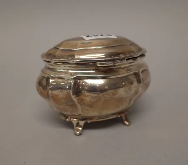 A late Victorian silver hinge lidded tea caddy, of panelled bombe form, raised on four feet, London 1899, weight 178 gms.