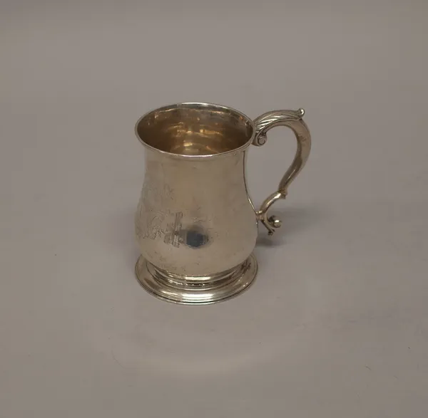 A late George II silver mug, of baluster form with a scrolling handle, the body engraved with a coat of arms, London probably 1750, height 9.5cm, weig