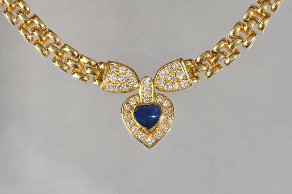 A gold, sapphire and diamond pendant necklace, the front mounted with a heart shaped cabochon sapphire, in a surround of circular cut diamonds, betwee