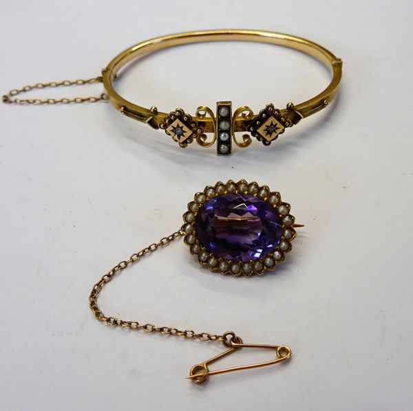 A gold, amethyst and seed pearl set oval brooch, mounted with the oval cut amethyst in a surround of seed pearls, detailed 15 CT, with a safety chain