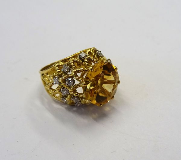 A gold, citrine and diamond ring, claw set with the large circular cut citrine to the centre within a lattice work raised surround, claw set with circ