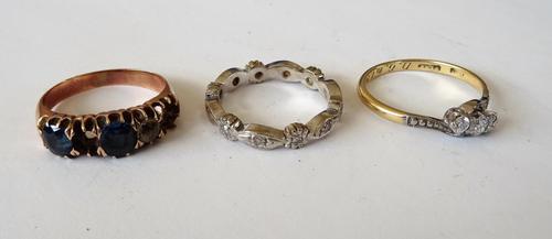 A gold and platinum, diamond set three stone ring, claw set with a row of circular cut diamonds in a crossover design, detailed 18 CT PLAT, a white go