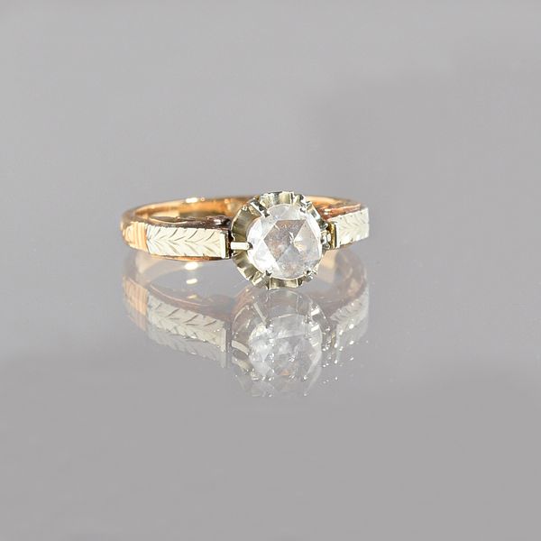 A gold and rose diamond single stone ring, claw set with the single rose diamond between scroll engraved two colour shoulders, ring size K. Illustrate