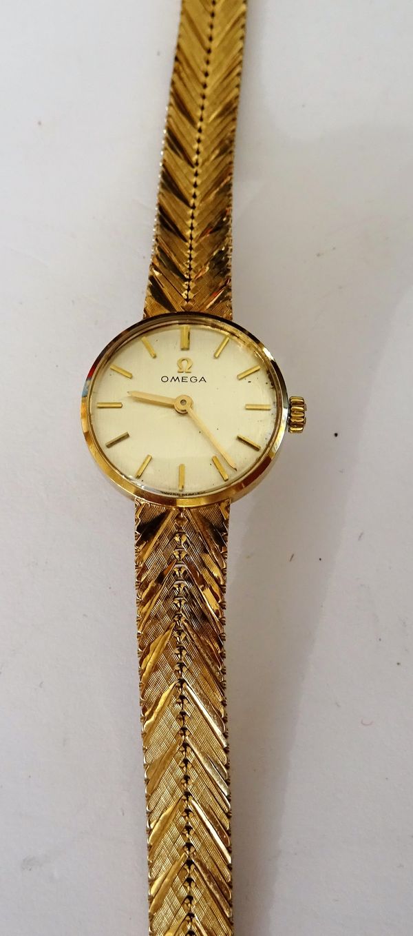 An Omega 9ct gold, circular cased lady's bracelet wristwatch, the signed -ilvered dial with gilt baton numerals, on a 9ct gold tapering herring bone l