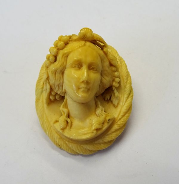 A Victorian carved ivory cameo brooch, designed as the portrait of a bacchante, with fruiting vine within a ropetwist border.