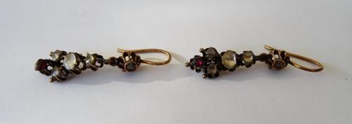 A pair of rose diamond and ruby pendant earrings, each mounted with a cushion shaped ruby to the bottom of the drop, above four rose diamonds and with