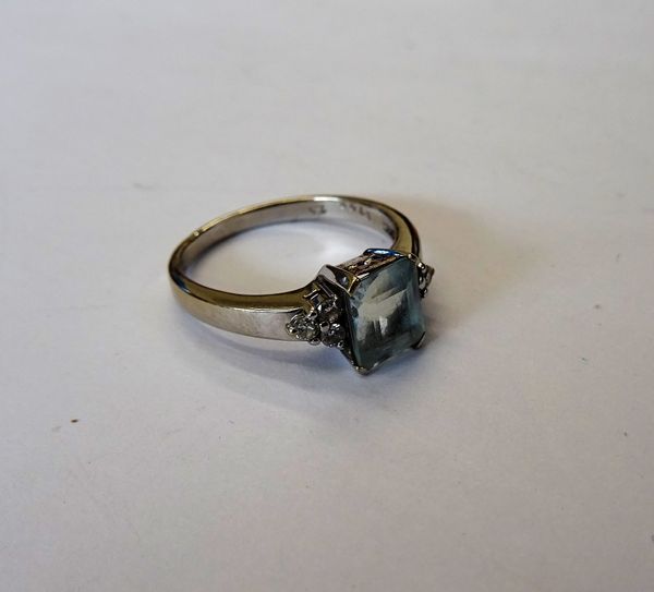 A white gold, aquamarine and diamond ring, claw set with the rectangular step cut aquamarine to the centre, between circular cut diamond set three sto