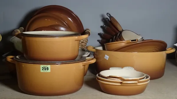 A large quantity of brown cast iron Le Creuset cookware.