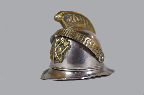 An early 20th century novelty match striker in the form of a fireman's helmet, hinged naturalistic lid with dragon decorated crest above interior with