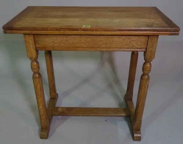 An early 20th century oak foldover card table on octagonal turned supports united by 'H' frame stretcher, 76cm wide x 70cm high.