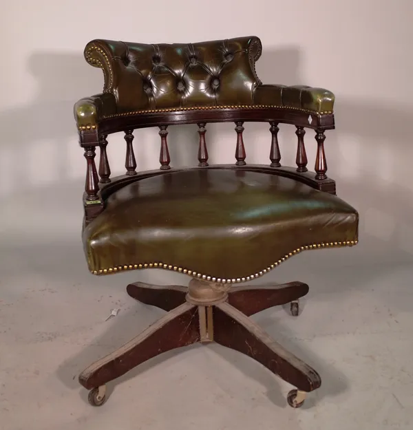 A 20th century mahogany framed revolving chair with green leather studded upholstery.