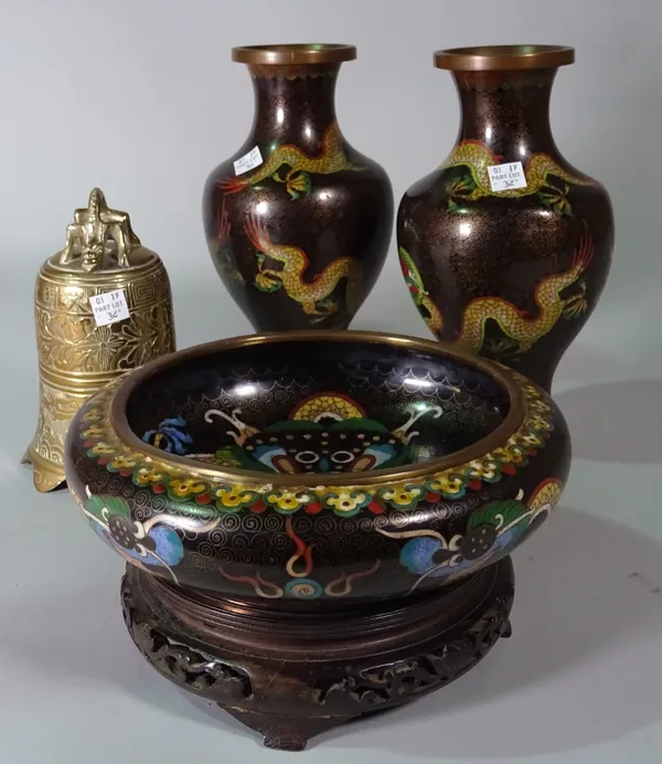 A 20th century cloisonné black ground bowl decorated with a dragon and a matching pair of baluster vases, (a.f) and a Chinese polished brass bell, (4)