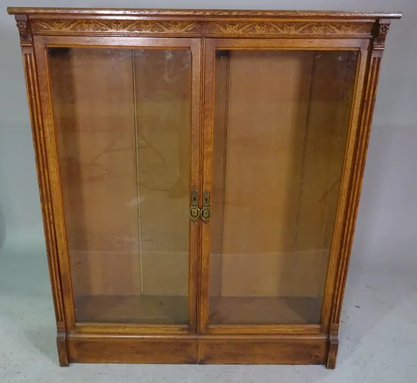 An early 20th century oak two door bookcase with carved decoration, 110cm high x 105cm wide.