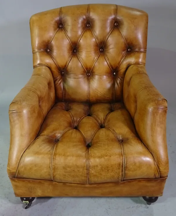 A brown leather upholstered button back easy armchair on turned supports, 80cm wide x 97cm high.