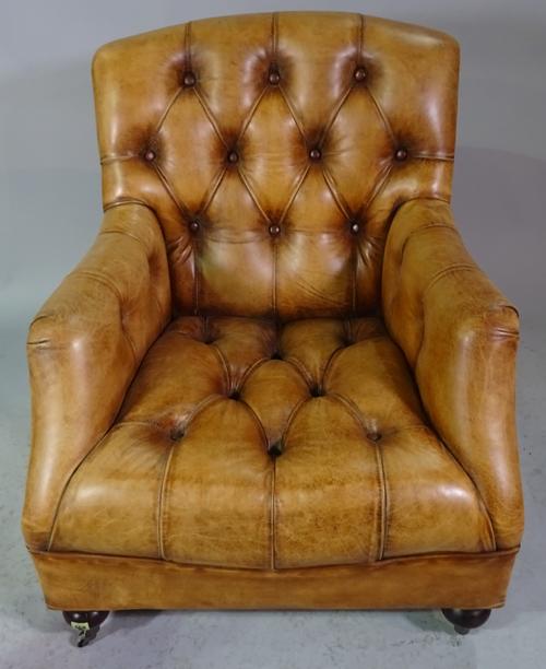 A brown leather upholstered button back easy armchair on turned supports, 80cm wide x 97cm high.