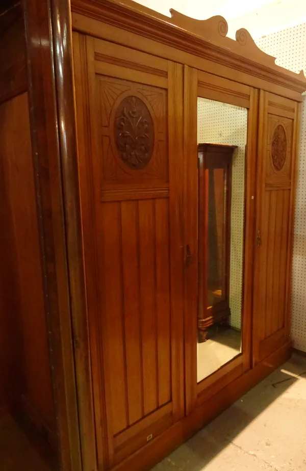 A 19th century satinwood serpentine triple wardrobe with carved panel doors on plinth base, 181cm wide x 200cm high.