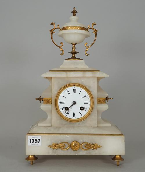 An alabaster mantel clock, late 19th century, with gilt metal mounts and urn surmount over a white enamel dial and plinth base, 39cm high, (pendulum).