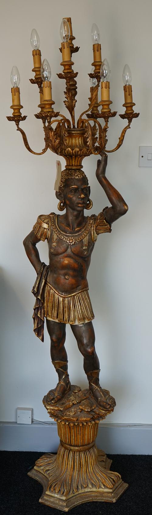 A pair of mid-20th century carved wooden figural candelabra, each Nubian male supporting ten foliate branches over a quadraform base, 187cm high, (2).