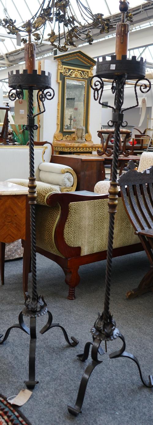 A pair of 17th century style wrought iron standard lamps, each with castellated circular rim, brass mounted spiral twist column and triform scroll fee