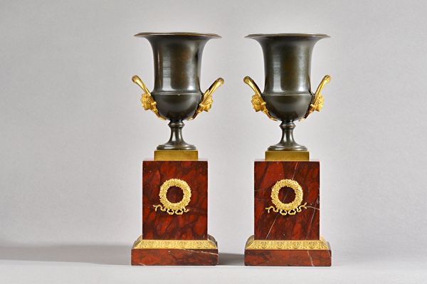 A pair of restoration ormolu mounted bronze and rouge girotte marble campana urns, circa 1830, each raised on a square form pedestal, 29.5cm high.  Il