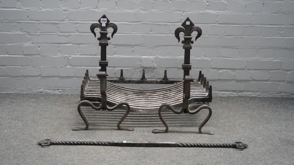 A cast iron fire basket on fleur de lis cast andirons with a wrought iron log holder of scrolling form, fire basket 75cm wide.