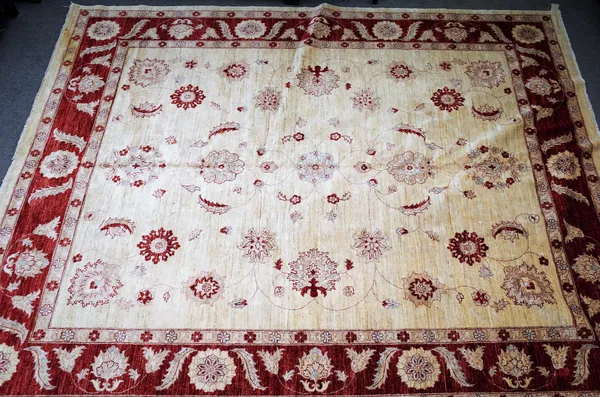 A modern Persian carpet, the ivory field with delicate madder, single palmettes, leaves and bold flowerheads, a madder palmette and leaf border, 352cm