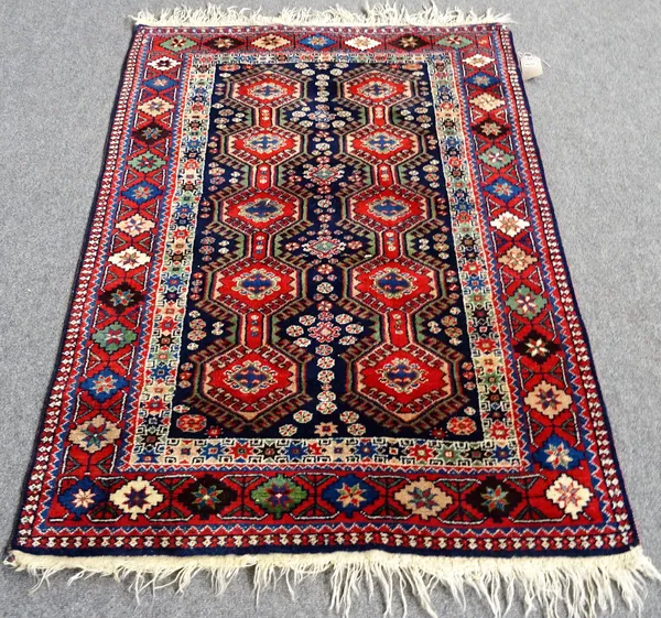 A South Persian rug, deep blue filed with parallel rows of pole medallions of hexagonal form, deep red border with polychrome floral decoration, 153cm