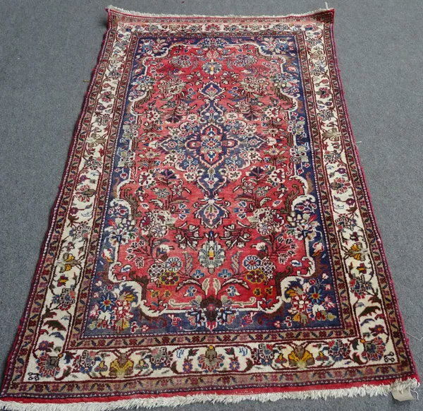 A Sarough rug, Persian, the madder field with an indigo diamond medallion, indigo outer surround, all with floral sprays, an ivory matching border, 21