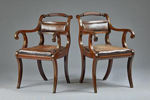 A pair of Regency brass inlaid mahogany library open armchairs with reeded crest rail and sabre supports, 52cm wide x 84cm high, (2). Illustrated.