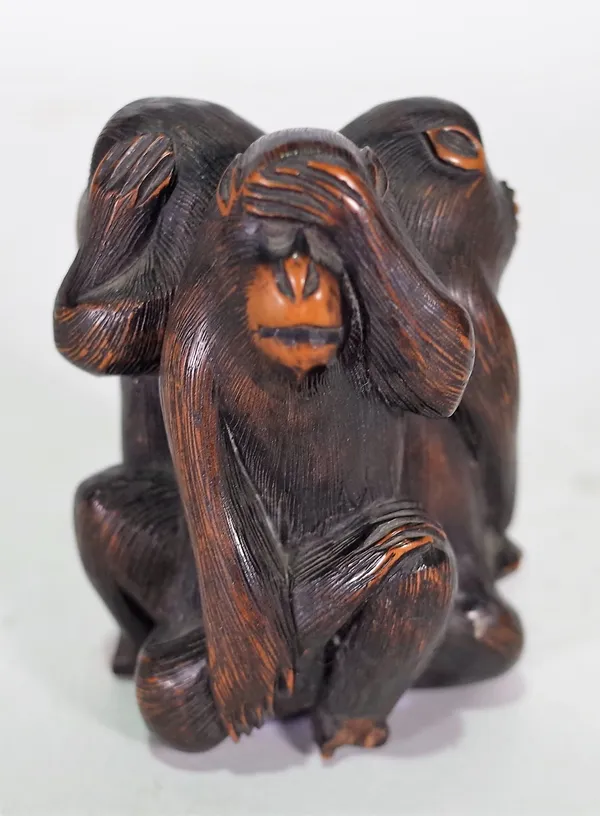 A Japanese wood okimono of the three wise monkeys, 20th century, carved seated back to back, (a.f), 8cm. high.