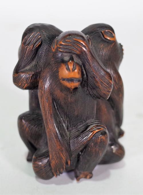 A Japanese wood okimono of the three wise monkeys, 20th century, carved seated back to back, (a.f), 8cm. high.