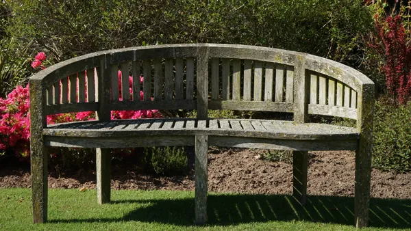 A pair of 20th century teak kidney shaped garden benches of slatted construction, 155cm wide x 87cm high, (2).