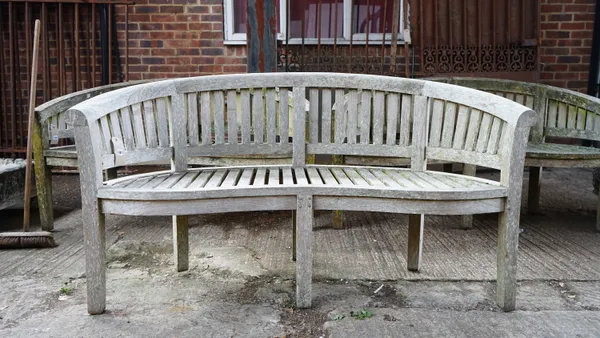 A 20th century teak kidney shape bench of slatted construction, 160cm wide x 90cm high.