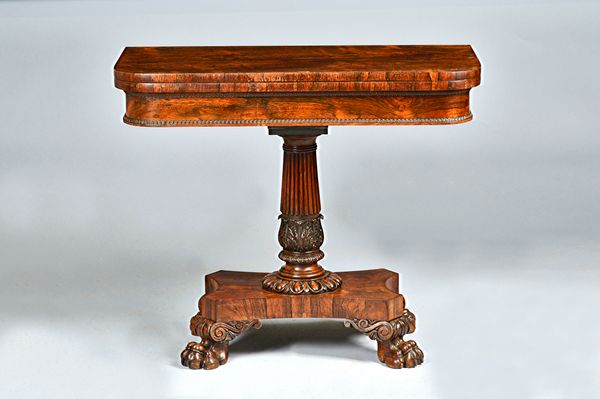 A William IV rosewood card table, with foldover 'D' shape top on reeded column on four lion's paw feet, 91cm wide x 76cm high.Illustrated.