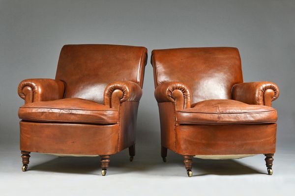 A pair of early 20th century French brown leather upholstered easy armchairs, on turned walnut supports, 85cm wide x 86cm high, (2). Illustrated.