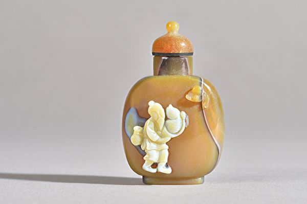 A Chinese cameo agate snuff bottle, 19th century, carved in high relief with a fisherman standing with a large fish, 6cm. high. Provenance: Christie's